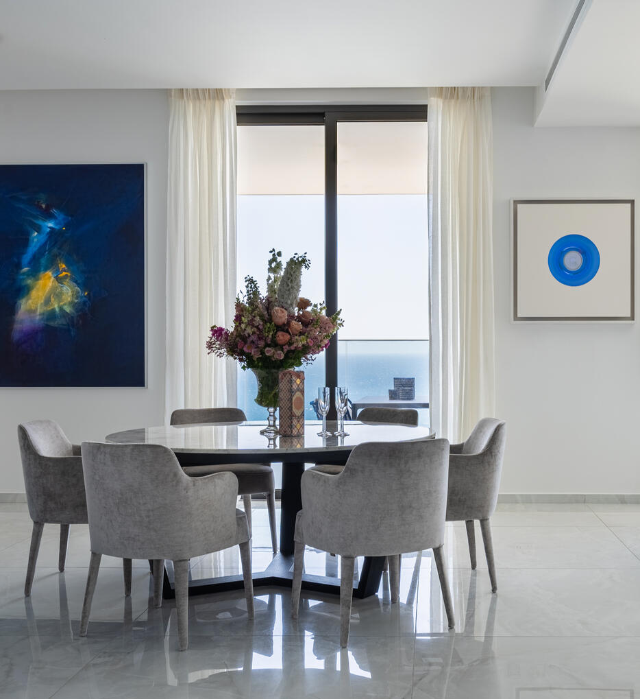 Interior photography of an elegant dining area in a high-rise apartment in Limassol, Cyprus, with sea views, floral details and contemporary artwork.