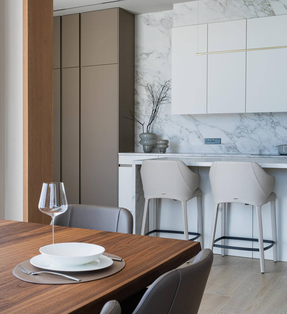 Interior photography of an open-plan dining and kitchen area, showcasing the connection between the spaces, natural tones and warm wood details.