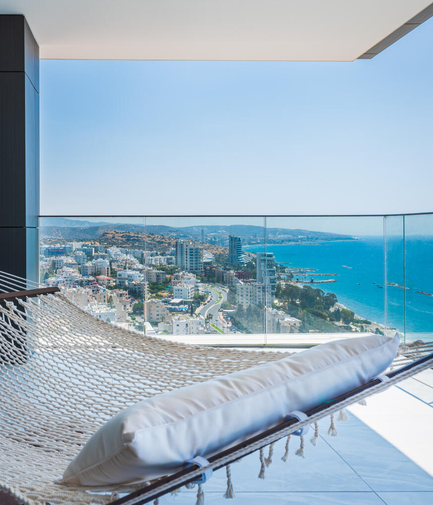 Real estate photography of a high-rise apartment in Limassol, Cyprus, featuring a sea view and balcony with a hammock.